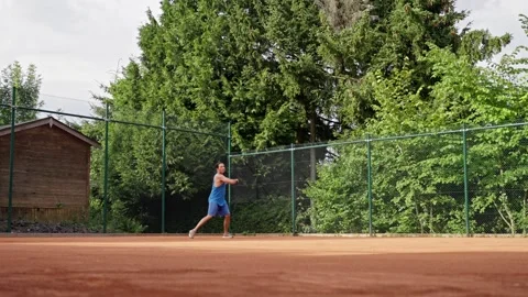 A dedicated player practices tennis skillfully on a clay court that is Video stock 317198746