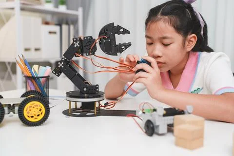 Dedicated schoolgirl, observing the prototype of robotic car, she testing Stock Photos