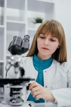 A dedicated scientist in a white lab coat and blue uniform is carefully adj.. Stock Photos