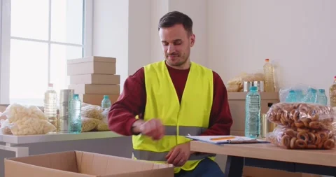 Dedicated volunteer smiles warmly while holding red heart symbol, representing Stock Footage 336668697