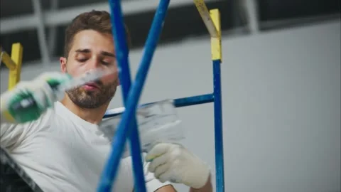 A Dedicated Worker Engaged in Painting a Wall while Balancing on a Ladder Stock Footage 316065983