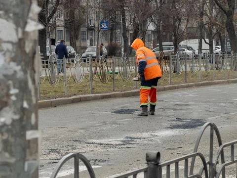 A dedicated worker in high visibility reflective gear manually patches deep.. Stock Photos