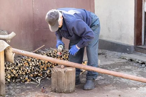 A dedicated worker uses an electric angle grinder to cut a metal pipe outdo.. Stock Photos