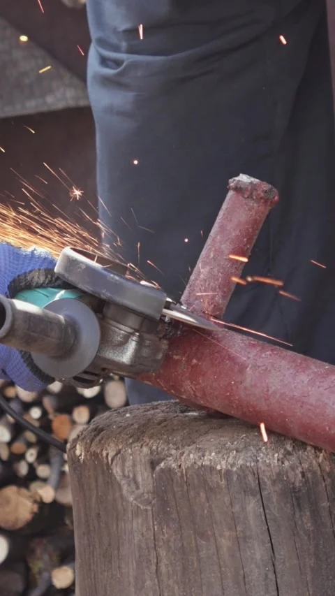 A dedicated worker uses a handheld power grinder to cut metal pipe in a bus.. Stock Footage 339084681