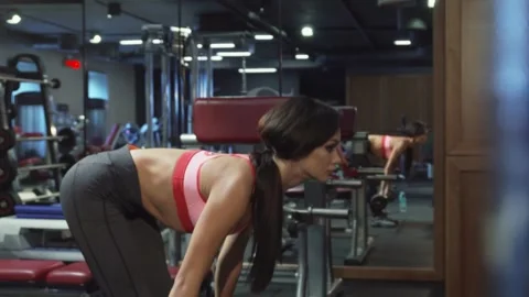 Dedicated young woman performs forward bends with a barbell, showcasing strength Stock Footage 311990272