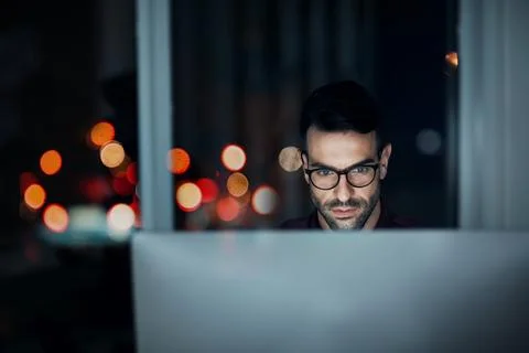 Dedication from A.M to P.M. a young businessman using a computer at his desk Stock Photos