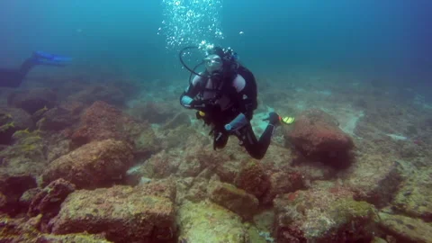 Deep beneath surface of water divers explore sunken remains of ship studying. Stock Footage 235042312