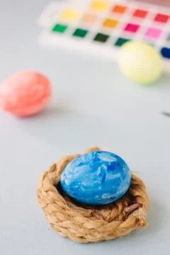 Deep blue easter egg on nest over bright background. Stock Photos