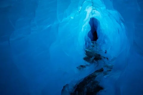 Deep blue ice inside of a glacial ice cave. This tunnel was carved by water m Stock Photos