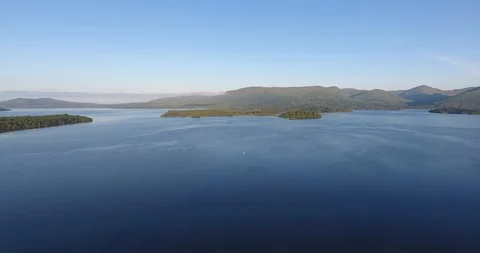 Deep Blue Lake Drone Shot with Hilly Landscape in the Distance 動画素材 97572066