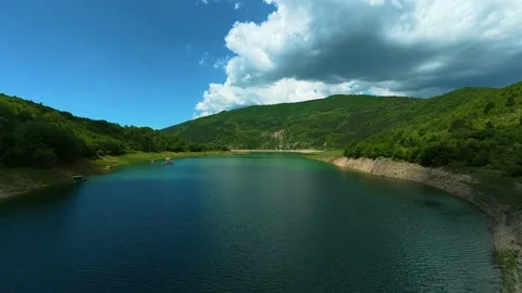 Deep blue lake reflects distant green hills. Zavoj Lake, Serbia Stock Footage 337489004