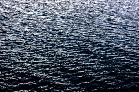 Deep blue ocean texture with cold evening light. Rhythmic sea waves pattern. Stock Photos