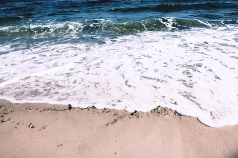 Deep blue ocean waves roll onto the sandy shore Stock Photos