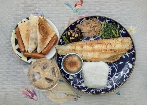 A deep-blue patterned plate holds a grilled Shima Hokke fillet, white rice,.. Stock Photos