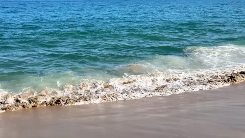 Deep blue sea water with white foam and splash hitting the beach coastline Stockbeeldmateriaal 337060215