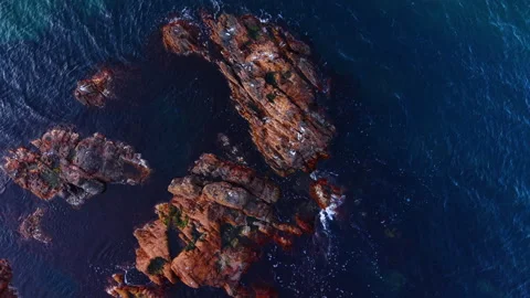 Deep blue seascape around the bare rocks. Waves splash by the brown rocks Video stock 321902752