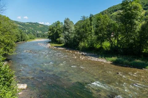 A deep blue sky with clouds and the mountains below and the current river wit Stock Photos