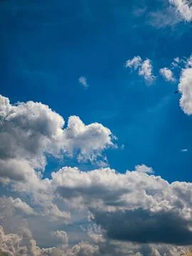 Deep Blue Sky with Dramatic White Cumulus Clouds, Vertical Nature Background Stock Photos