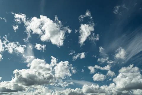 Deep blue sky filled with bright white cumulus clouds, calm summer weather Stock Photos