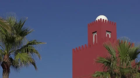 Deep blue sky red castle contrast palm trees castellations Stock Footage 57234559