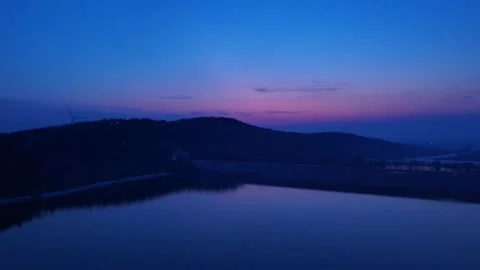 Deep Blue Twilight Over Lake Mountain and Wind Turbine China Stock Footage 338313496