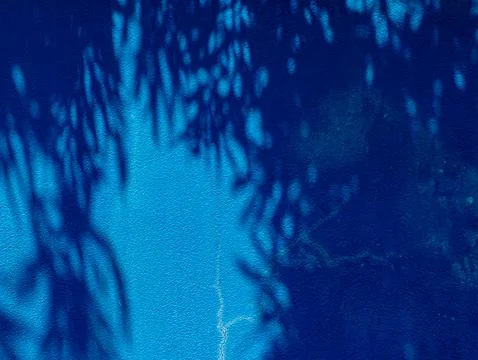 Deep Blue Wall with Dappled Tree Shadow Pattern and Faint Crack Line Stock Photos