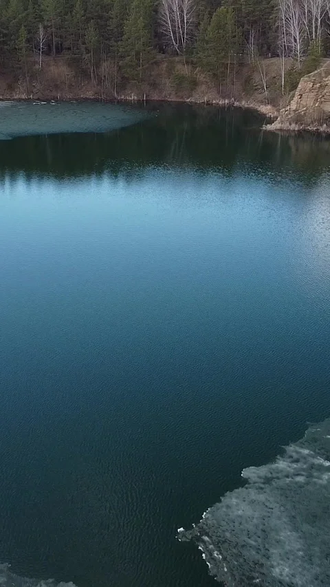 Deep blue water mirrors distant pine trees Stockbeeldmateriaal 347499348
