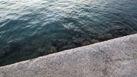 Deep blue water reflections next to a stone pier. Water reflections in harbor. Stock Footage 225633071