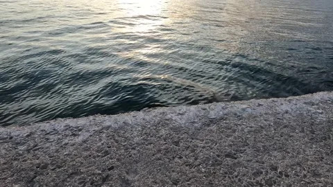 Deep blue water reflections next to a stone pier with sunset light. Stock Footage 225633084