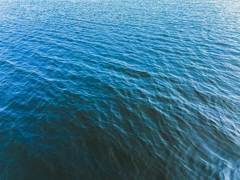 Deep blue water surface with gentle ripples and waves, natural aquatic text.. Stock-Fotos