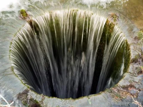 Deep bottomless pit with water flowing Stock Photos