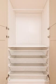 Deep built-in wardrobe white inside with open beige doors and pull-out white Stockfoto's