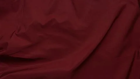 Deep burgundy cloth texture featuring soft wrinkles and flowing drapes to cre Stock Photos