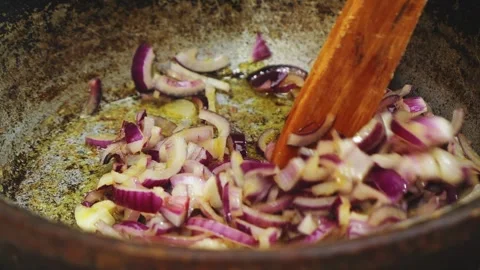 In a deep cast-iron skillet, chopped red onion is fried in vegetable oil an.. Stock Footage 340521979