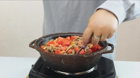 In a deep cast-iron skillet, onions and chicken are simmered in a sauce and.. Stock Footage 346725670