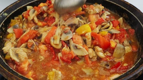 In a deep cast iron skillet, vegetables and meat are stewed in sauce and sp.. 库存影片 343984855