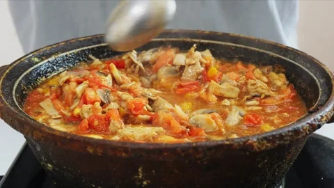 In a deep cast iron skillet, vegetables are stewed with chicken and mushroo.. 库存影片 343985559