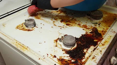 Deep cleaning a very dirty gas hob with a sponge and black gloves Stock Footage 341937052