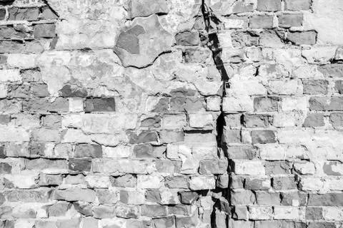 Deep crack in a brick wall. Black and white background. Stock Photos