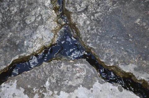 A deep crack in the road surface is filled with water after rain Foto stock