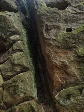 A deep crevice separates two large rock formations covered in moss Stock Photos