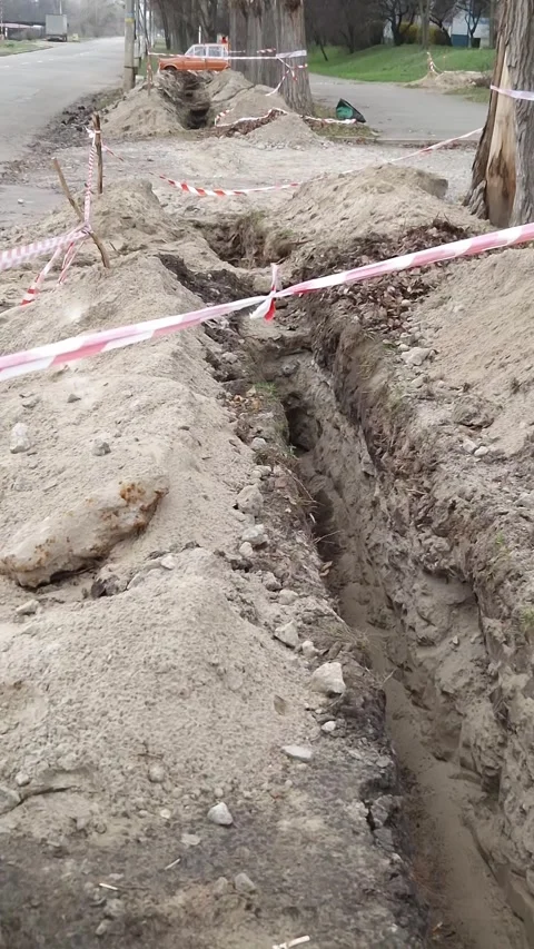 Deep Earthen Trench with Red and White Safety Tape Stock Footage 326202418