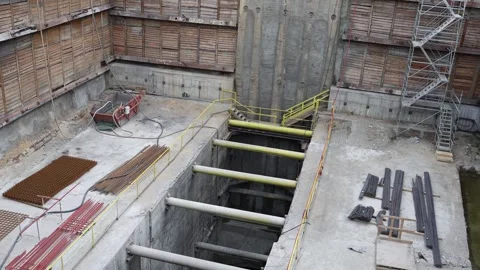 Deep excavation site with structural steel supports and rebar stacks bordered by Stock Footage 309655192