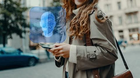 Deep fake technology is shown through a person using a smartphone in an urban Stock Photos