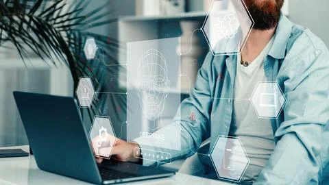 Deep fake technology usage shown in an office setting with a man working on a Stock Photos
