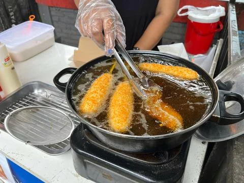 Deep fried corn dog stuffed with cheese and sausage in oil Stock Photos