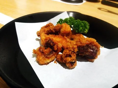 Deep fried crispy squid tentacles on black dish or plate Stock Photos