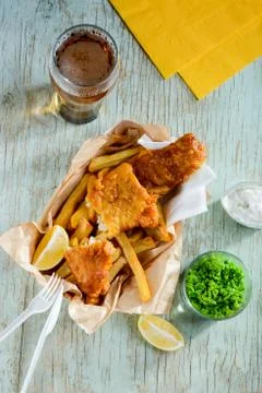 Deep fried fish and chips in combination with lemon slices, green peas and beer Stock Photos