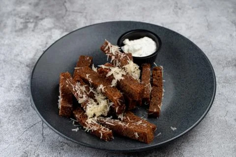Deep fried rye croutons with grated parmesan cheese and garlic sauce on grey  Stock Photos
