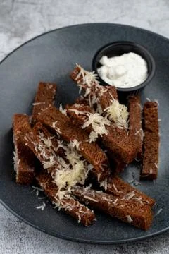 Deep fried rye croutons with grated parmesan cheese and garlic sauce on grey  Stock Photos